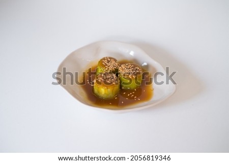 Zucchini in sauce with sesame seeds on white plate isolated on white. Close up, healthy food, healthy lifestyle, picture for the menu, vegetarian