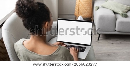 Young woman working at home, student girl using laptop computer with blank white empty screen monitor mock up. Online shopping, web site, working from home, online learning, studying concept.