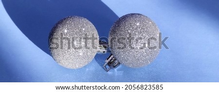 Minimal Christmas composition with two silver glitter balls toys on blue background.  Christmas, winter, new year concept. Flat lay, top view, copy space