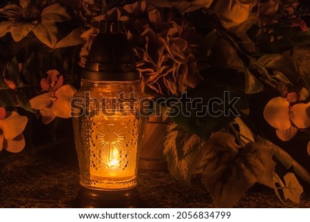 Orange grave lantern shining with light. Cemetery at night. Catholic Halloween tradition. All souls' day in Poland, Eastern Europe. Zaduszki. Royalty-Free Stock Photo #2056834799