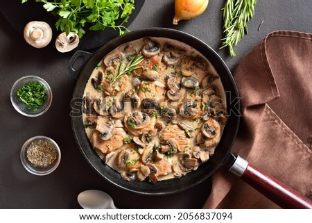 Pork medallions with mushroom gravy in cast iron pan over dark stone background. Top view, flat lay Royalty-Free Stock Photo #2056837094