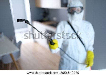 Person in protective suit and mask disinfects kitchen