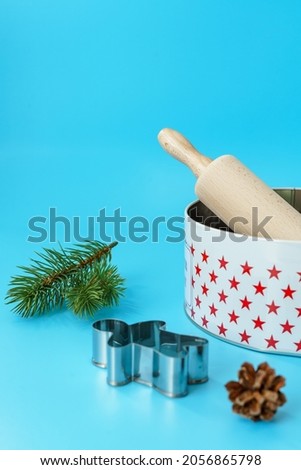A rolling pin, cookie cutters and a cookie jar on a blue isolated background. Vertical, Christmas background. 