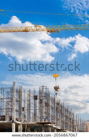 Working at height equipment with bucket liquid concrete container. Construction worker working on a high building. Crane lifting Cement mixer machine to  building. Crane lift concrete mixer container