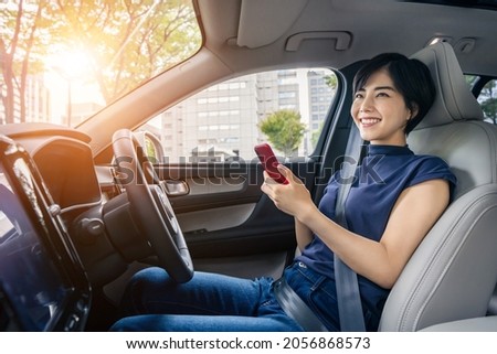 Young asian woman using a smart phone in the car. Royalty-Free Stock Photo #2056868573