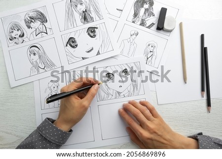 An artist draws a storyboard of an anime comics book. Manga style. Royalty-Free Stock Photo #2056869896