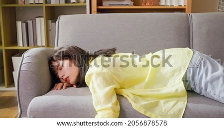 asian woman feels tired so she sleeps on sofa at home after studying or working Royalty-Free Stock Photo #2056878578
