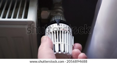 turning down thermostat on radiator to save energy due to heating cost price hike Royalty-Free Stock Photo #2056894688