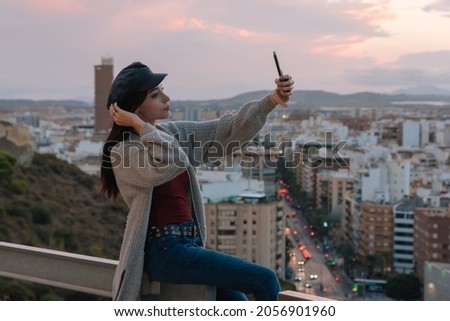 young woman makes a self portrait with her mobile outdoors