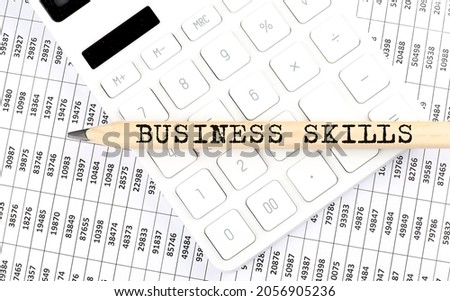 text BUSINESS SKILLS on the wooden pencil on the calculator with chart
