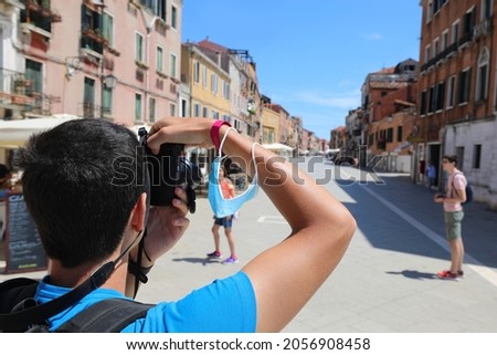 young boy takes pictures of the city of Venice with very few people during the lockdown