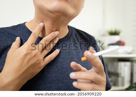 Neck of male smoker have a sore throat,painful and inflammation caused by smoking,man patient holding a cigarette has phlegm in his throat suffering from laryngeal cancer,throat cancer disease concept Royalty-Free Stock Photo #2056909220