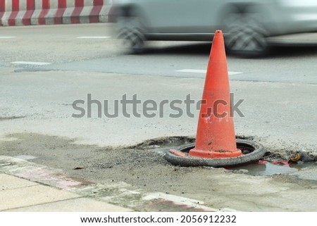 orange traffic cone  Placed on a bumpy road surface.  so that the car traveling can see the symbol clearly to prevent accidents  blur background