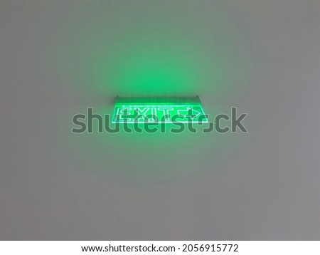 green neon light exit sign points the way out of building