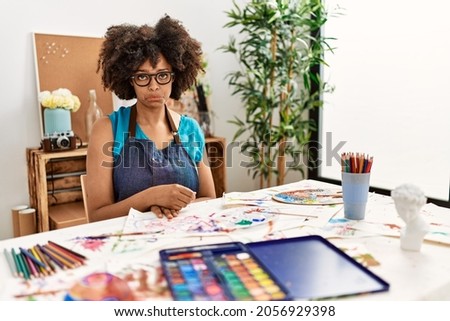 Beautiful african american woman with afro hair painting at art studio depressed and worry for distress, crying angry and afraid. sad expression. 