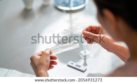 Asian woman using rapid antigen test kit for self test COVID-19 epidemic at home. Adult female unpacking a swab for inserts into her nose. COVID-19 coronavirus pandemic protection concept. Royalty-Free Stock Photo #2056931273
