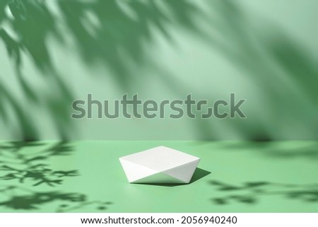 Abstract minimal nature scene - empty stage and polygonal podium on pastel mint green background and soft tree leaves shadows. Pedestal for cosmetic product and packaging mockups display presentation Royalty-Free Stock Photo #2056940240