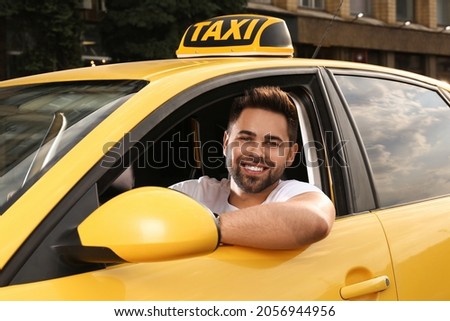 Handsome taxi driver in car on city street Royalty-Free Stock Photo #2056944956