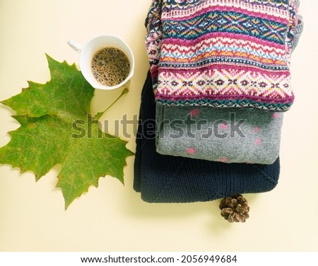 Modern concept of green leaf, coffee, cone and warm, cozy sweaters.