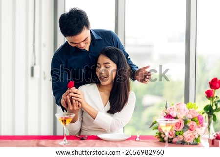 Young handsome man giving ring for surprise to girlfriend and talking together in valentine day at the restaurant