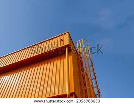 The building is constructed with metal sheet material. painted in yellow throughout with a background of a blue sky during the day. Royalty-Free Stock Photo #2056988633