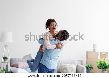 Happy couple moving at bought house, husband lifts up beloved wife, family begin new life at first dwelling, copy space. Loan and mortgage, bank lending, relocation at own apartment, rent flat Royalty-Free Stock Photo #2057011619