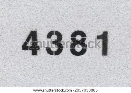 Black Number 4381 on the white wall. Spray paint. Number four thousand three hundred and eighty one.