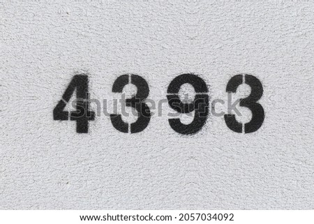 Black Number 4393 on the white wall. Spray paint. Number four thousand three hundred ninety three.