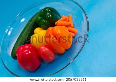 Different types of vegetables and a tomato isolated on blue background in a concept tomato is fruit, not vegetable.