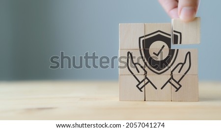 Work safety concept, hazards, protections, health and regulation.  Concept of data security. Hand holds wooden cubes with hand holding protect shield symbol on grey beautiful background. Copy space Royalty-Free Stock Photo #2057041274