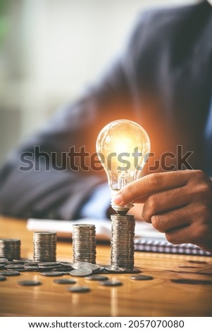 Savings business accountant hand holding financial light bulb concept financial background on the table where the morning sun shines Royalty-Free Stock Photo #2057070080