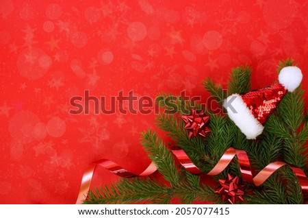 Christmas card with santa hat and spruce branches. Red background with copy space. High quality photo