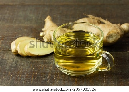 Ginger tea in transparent glass and fresh ginger with sliced on wooden background. The scientific name is zingiber officinale. Herbs for health care concept.