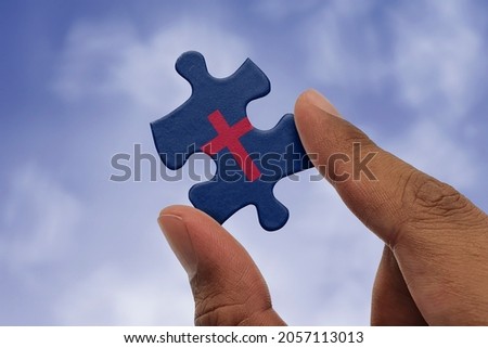 Hand holding piece of jigsaw puzzle with flag of Christianity. Religious symbols of Christianity.