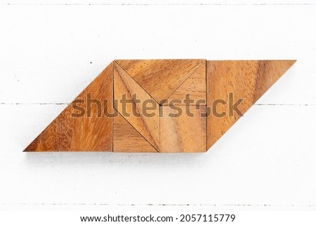 Wood tangram puzzle in parallelogram shape on white wood background