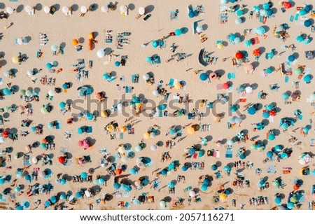Drone shot of many people enjoying the beach and the ocean in high season - vacation pattern.