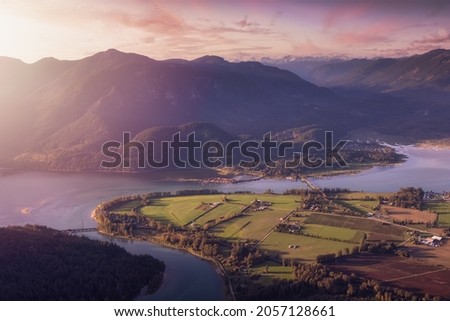 Aerial View of Fraser Valley with Canadian Nature Mountain Landscape Background. Colorful Sunset Sky Art Render. Harrison Mills near Chilliwack, British Columbia, Canada. Royalty-Free Stock Photo #2057128661