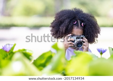 Cute afro curly girl Young women take pictures of old cameras Taking lotus flowers in the garden, Nature study concept.