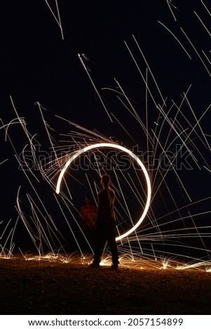 Iron wool circle drawing light fireworks. Burning Steel Wool spinning, Trajectories of burning sparks at night. Movement light effect, steel wool fire hoop. long exposure light painting, Pyrotechnic Royalty-Free Stock Photo #2057154899