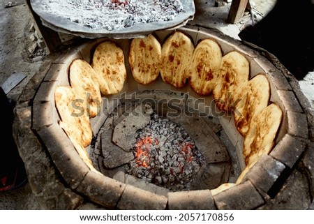 Bread in the tandoor. Traditional way of baking bread in the tandoor in Dagestan, Russia. Royalty-Free Stock Photo #2057170856