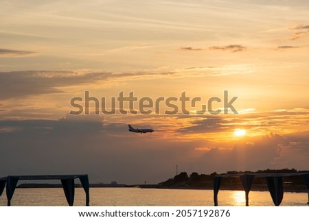 the silhouette of an airplane against the background of the sea, beach, mountains and the setting sun with clouds. He's coming in to land. a place to copy.