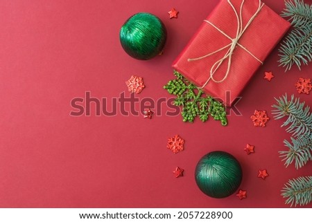 Flat lay frame with fir branches, christmas baubles decoration and gift box on a red background