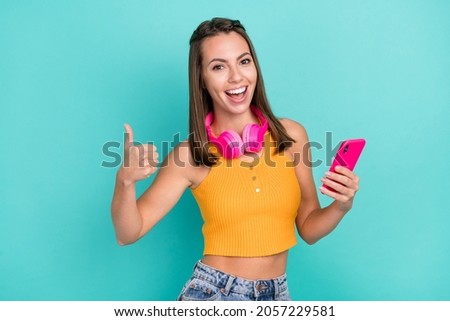 Photo of happy brunette positive lady show thumb up recommend smile blogger phone isolated on teal color background