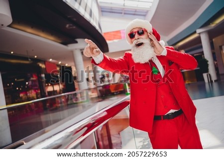Photo of excited santa grandpa indicate finger amazing novelty wear hat red suit in supermarket mall center