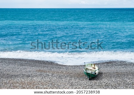 an old plastic fishing boat is near the water on the seashore. landscape with a boat