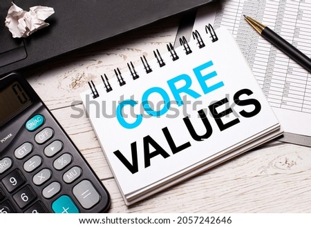 On a light-colored office table is a computer, a black calculator, a pen, and a notebook with the text CORE VALUES. Business concept.