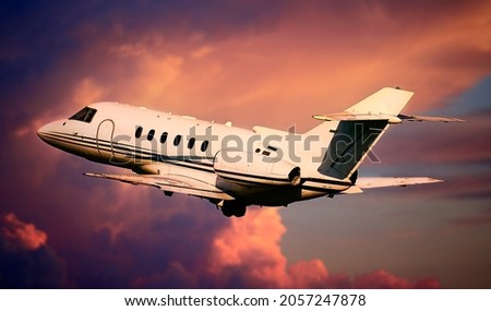 Private airplane jetliner flying above clouds in beautiful sunset light. Travel and business concept. Backside view Royalty-Free Stock Photo #2057247878