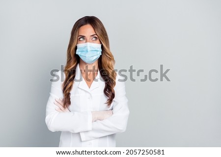 Photo of dreamy positive age lady doctor wear white formal coat arms crossed looking empty space isolated grey color background