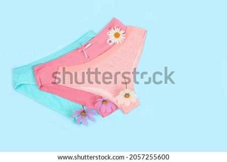 Assortment of womens cotton underpants with chamomile flowers on blue background with place for text, advertising of underwear for girls, concept of feminine hygiene and purity of intimate organs,