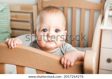 Baby 8 months on crib. Children's facial expressions, newborn care concept, healthy sleep, colic, teething.